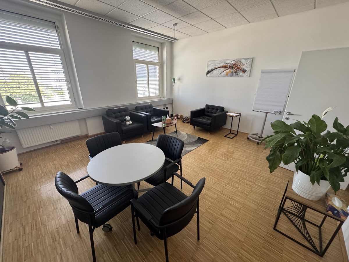 Praxisraum mit Ledersesseln, Rundtisch und Pflanzen